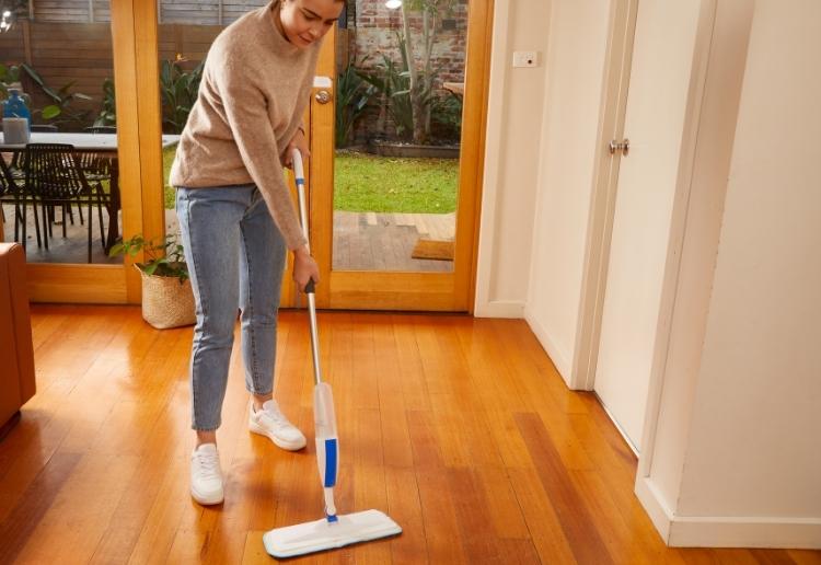 woman mopping wooden floors with the oates ezy spray mop