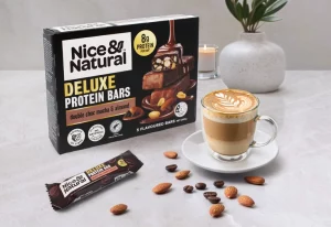 Nice and Natural Deluxe Protein Bars in mocha flavour next to a cup of coffee and some nuts.